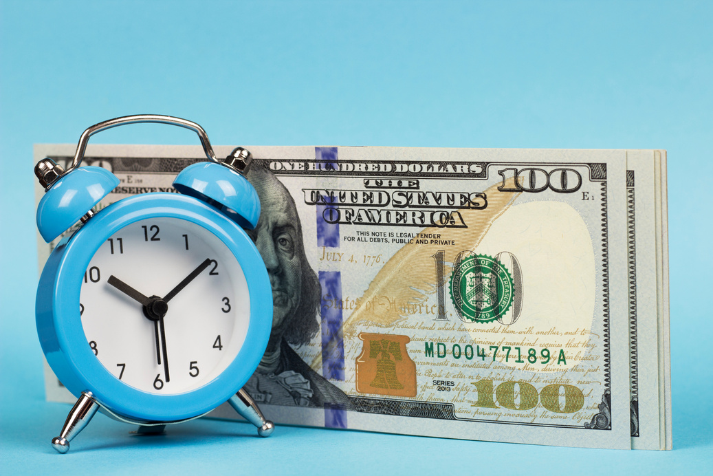 money and alarm clock on a blue background